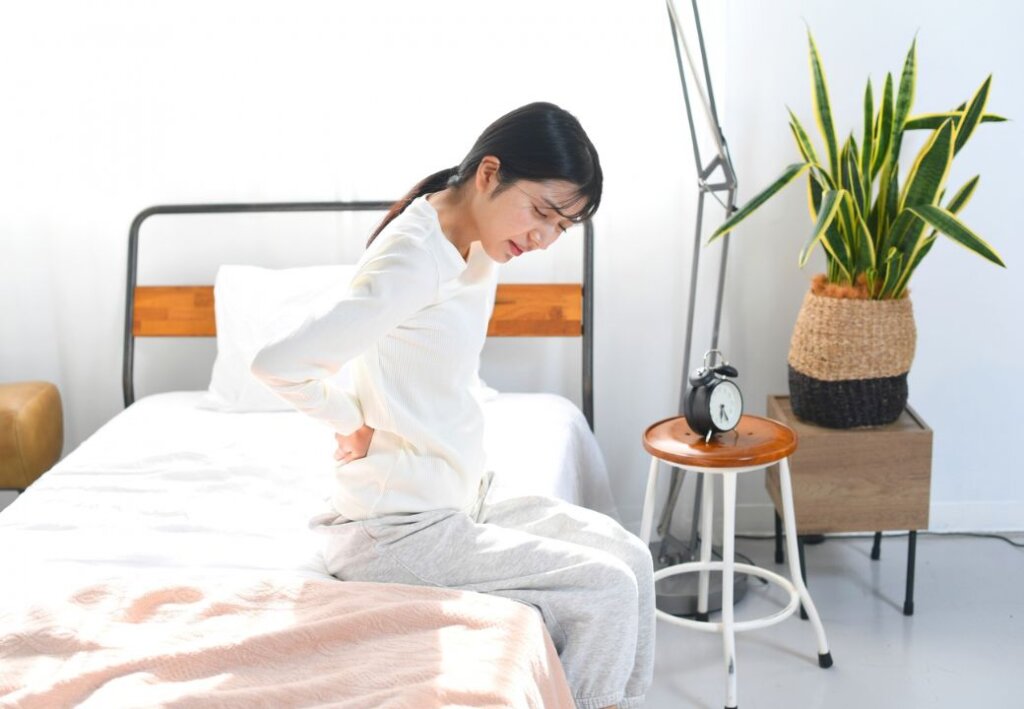 寝起きの腰痛に悩まされる女性